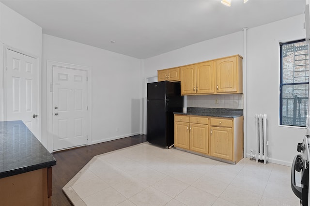 kitchen with radiator, stainless steel range, black refrigerator, and light wood-type flooring