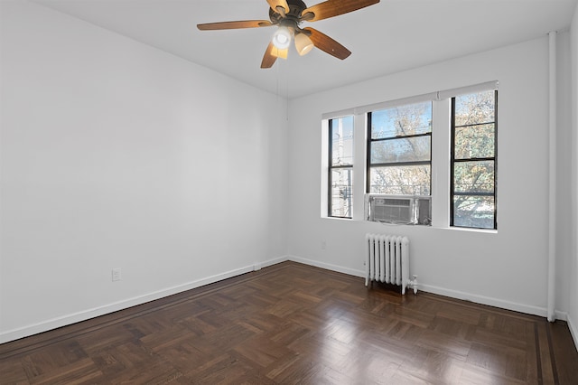 spare room featuring ceiling fan, radiator, and dark parquet floors