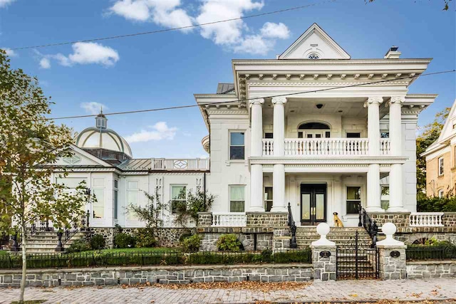 greek revival inspired property featuring a porch and a balcony