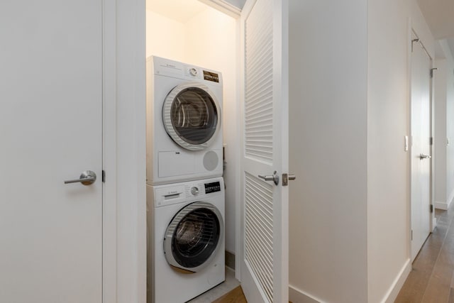 laundry area with light hardwood / wood-style floors and stacked washer / dryer