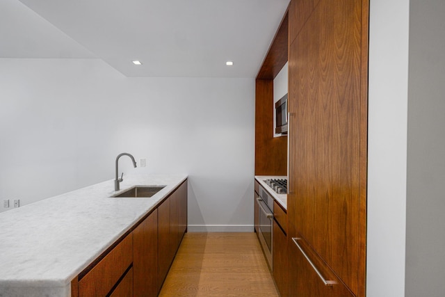 kitchen featuring kitchen peninsula, light wood-type flooring, sink, and appliances with stainless steel finishes