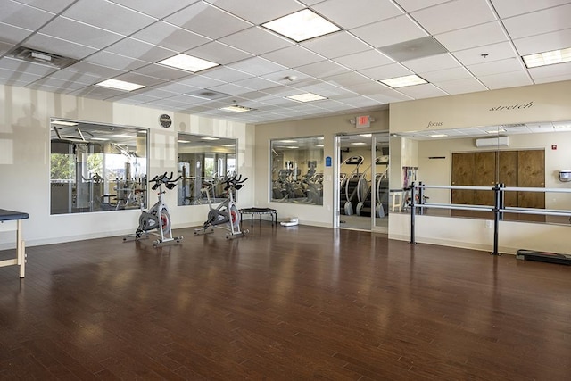 workout area featuring baseboards, a drop ceiling, wood finished floors, and visible vents