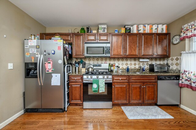 135 38th St Unit 407, Union City, NJ 07087 - kitchen featuring stone counters, a sink, backsplash, stainless steel appliances, and light wood-style floors