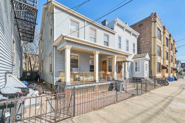 townhome / multi-family property featuring a fenced front yard and covered porch