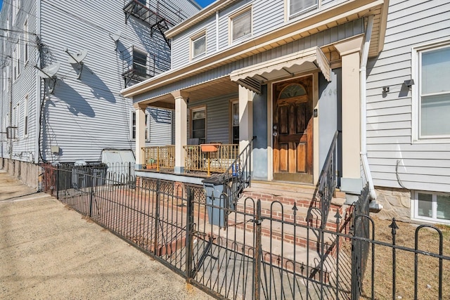 entrance to property featuring a porch and fence