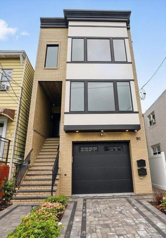 181 Bartholdi Ave Unit 2, Jersey City, NJ 07305 - view of front of property with brick siding, a garage, stucco siding, and stairway