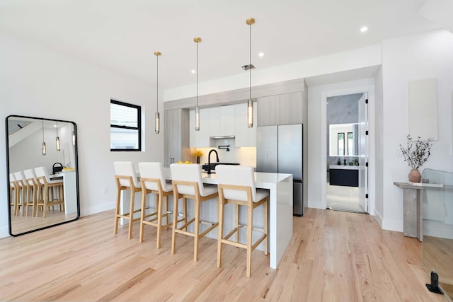 262 Webster Ave Unit 2, Jersey City, NJ 07307 - kitchen featuring freestanding refrigerator, light wood-style floors, a breakfast bar, light countertops, and a kitchen island with sink