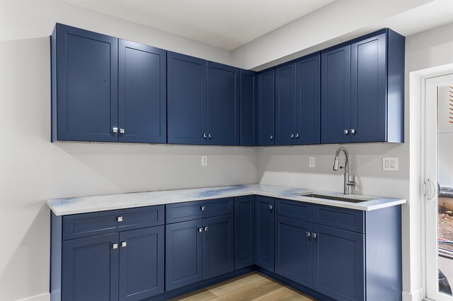 kitchen with light hardwood / wood-style floors, blue cabinets, and sink