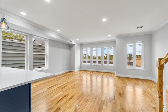 unfurnished living room with light wood-type flooring, ornamental molding, and a wealth of natural light