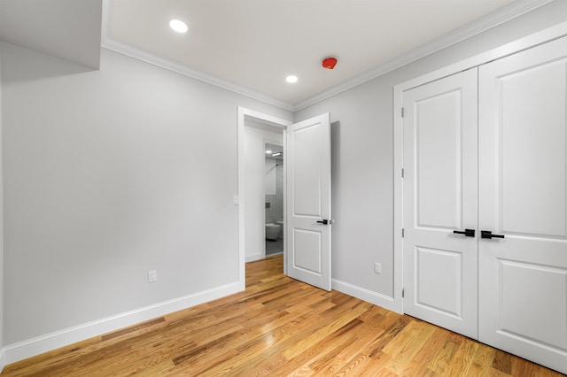 unfurnished bedroom with crown molding, a closet, and light hardwood / wood-style floors