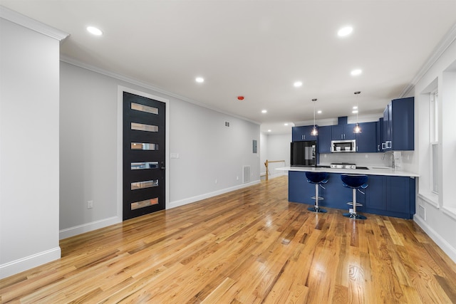 kitchen featuring a breakfast bar, black fridge, crown molding, blue cabinetry, and light hardwood / wood-style floors