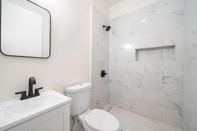 bathroom with vanity, toilet, and a tile shower