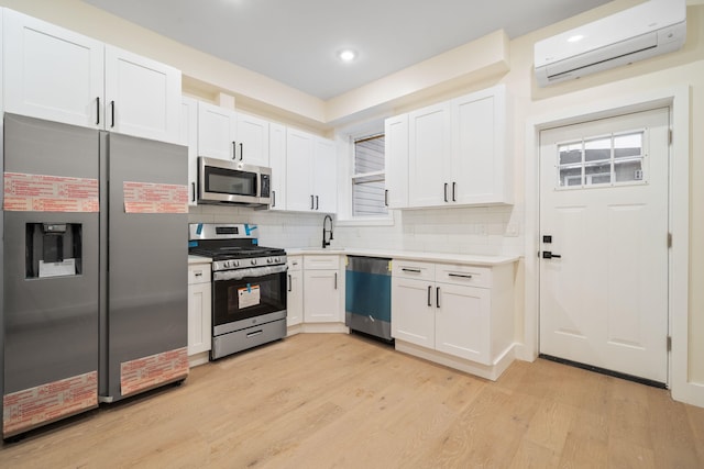 kitchen featuring white cabinetry, backsplash, stainless steel appliances, a wall mounted AC, and light hardwood / wood-style floors