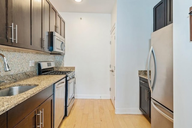 112 Liberty View Dr Unit 4B, Jersey City, NJ 07302 - kitchen featuring appliances with stainless steel finishes, dark brown cabinets, a sink, decorative backsplash, and light wood-style flooring