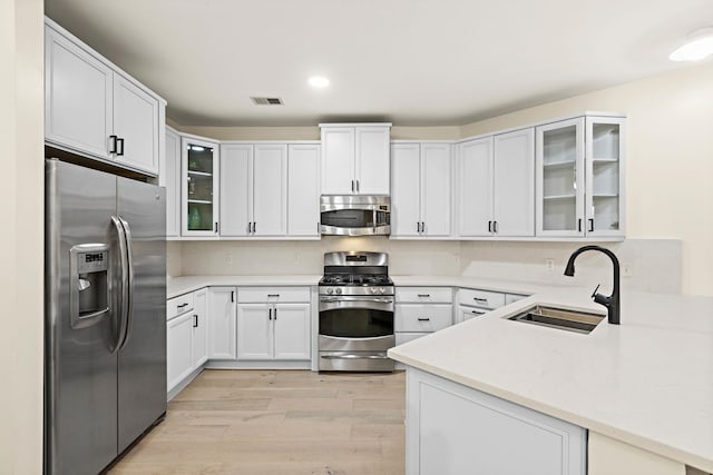 kitchen with sink, stainless steel appliances, light wood-type flooring, and white cabinets