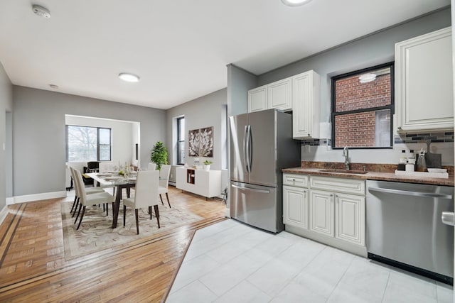 kitchen with stainless steel appliances, light hardwood / wood-style floors, white cabinets, decorative backsplash, and sink