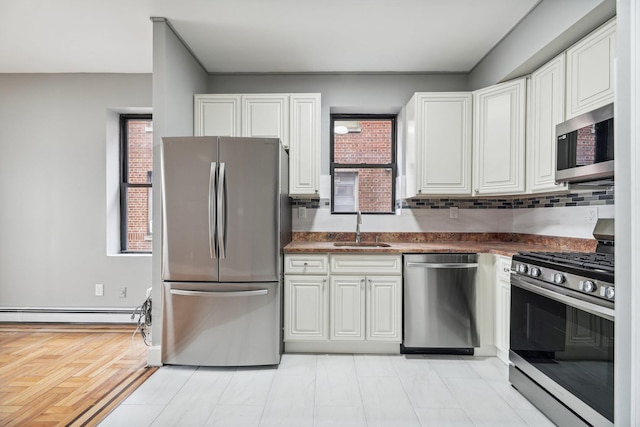 kitchen with sink, baseboard heating, backsplash, white cabinetry, and appliances with stainless steel finishes