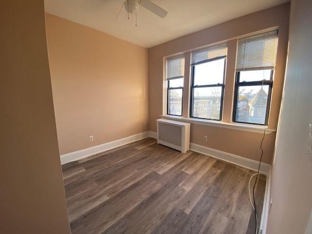 spare room with ceiling fan, dark hardwood / wood-style floors, and radiator heating unit