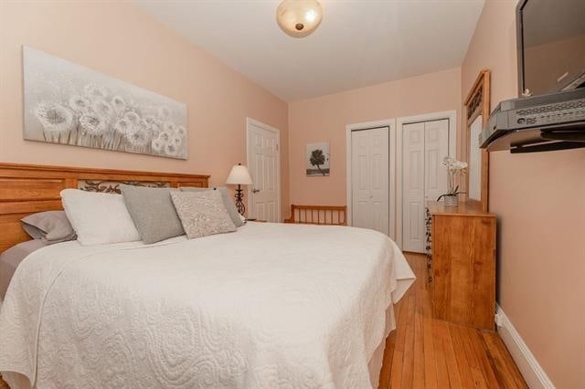 bedroom with multiple closets and light wood-type flooring