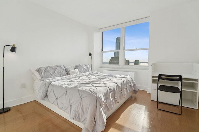 bedroom featuring baseboards, wood finished floors, and radiator heating unit