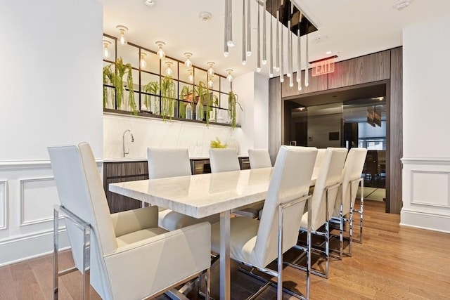 dining area featuring wood finished floors, wainscoting, and a decorative wall