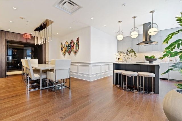 dining space featuring visible vents, wood finished floors, a wainscoted wall, a decorative wall, and recessed lighting