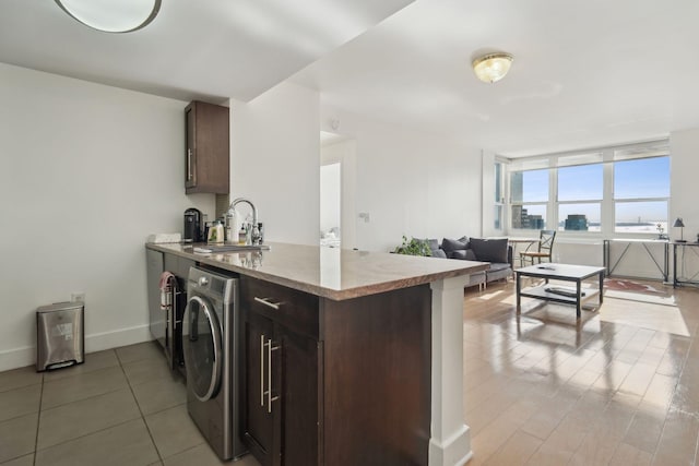 laundry room featuring laundry area, a sink, washer / clothes dryer, baseboards, and light tile patterned floors