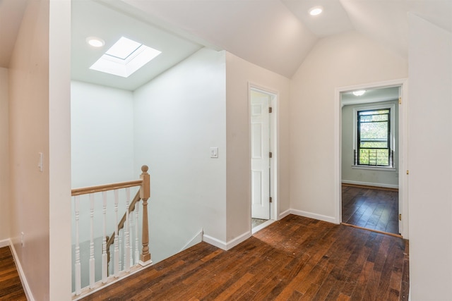 hallway featuring dark hardwood / wood-style floors and vaulted ceiling with skylight