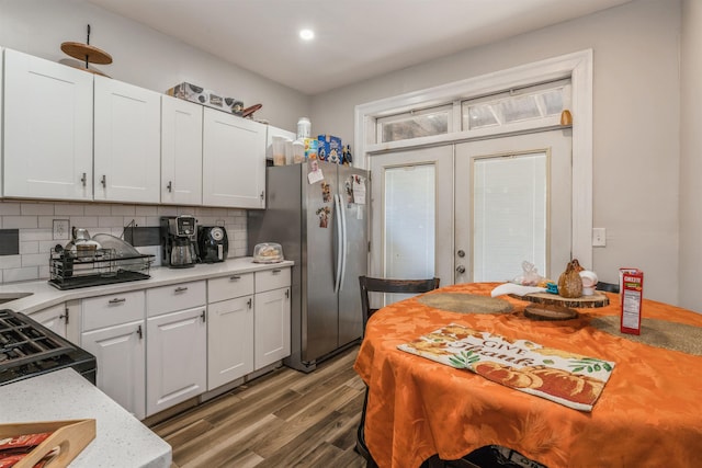 kitchen with hardwood / wood-style flooring, white cabinetry, stainless steel fridge, and backsplash