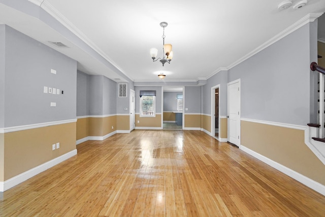 unfurnished living room featuring baseboards, light wood finished floors, ornamental molding, and an inviting chandelier