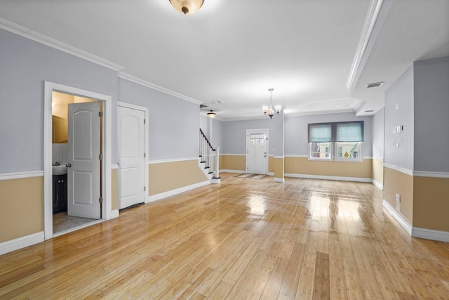 unfurnished living room featuring light wood-style flooring, visible vents, stairway, and ornamental molding