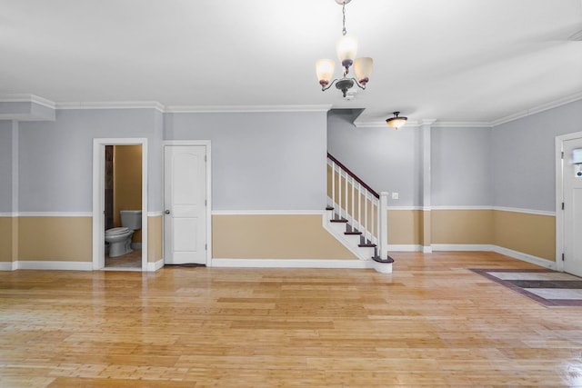 empty room with crown molding, stairway, light wood finished floors, and an inviting chandelier