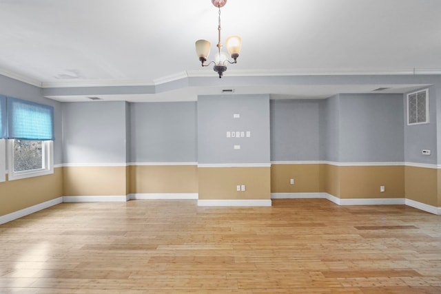 spare room with a chandelier, ornamental molding, light wood-style flooring, and baseboards