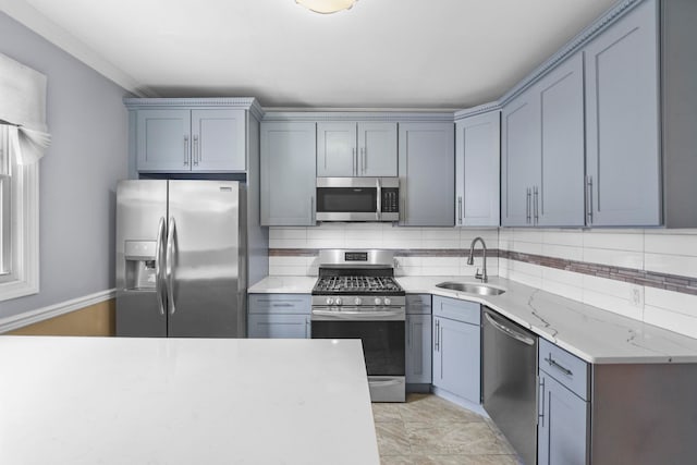 kitchen with appliances with stainless steel finishes, gray cabinets, a sink, and decorative backsplash