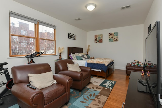 bedroom featuring baseboards, wood finished floors, and visible vents