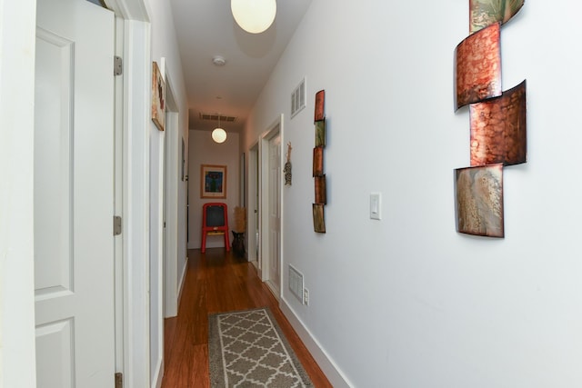 hall with visible vents, baseboards, and wood finished floors