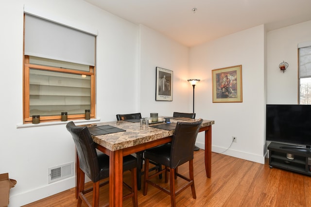 dining space with baseboards, visible vents, and wood finished floors