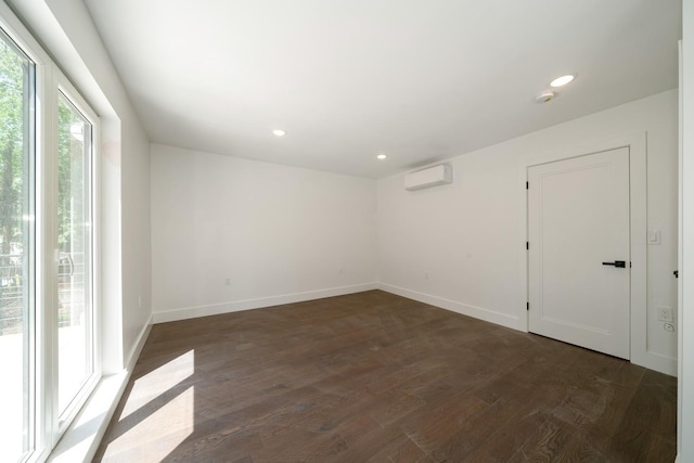 spare room with dark wood-style floors, an AC wall unit, and baseboards