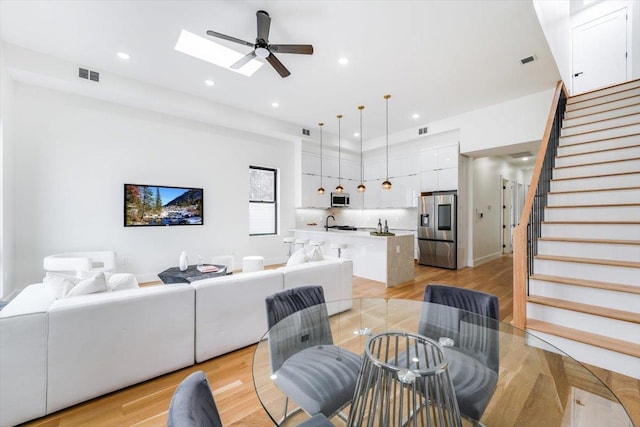 living room with visible vents, recessed lighting, stairway, and light wood-type flooring