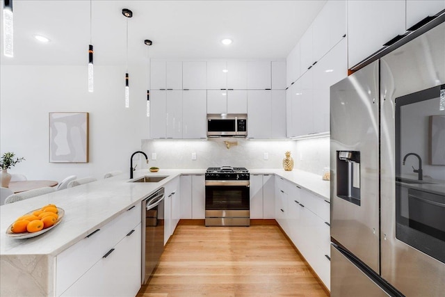 kitchen with modern cabinets, a sink, tasteful backsplash, stainless steel appliances, and a peninsula