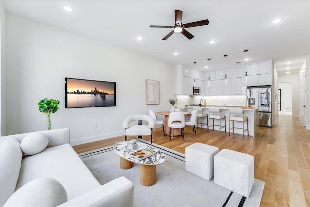 living area with recessed lighting, baseboards, ceiling fan, and light wood finished floors