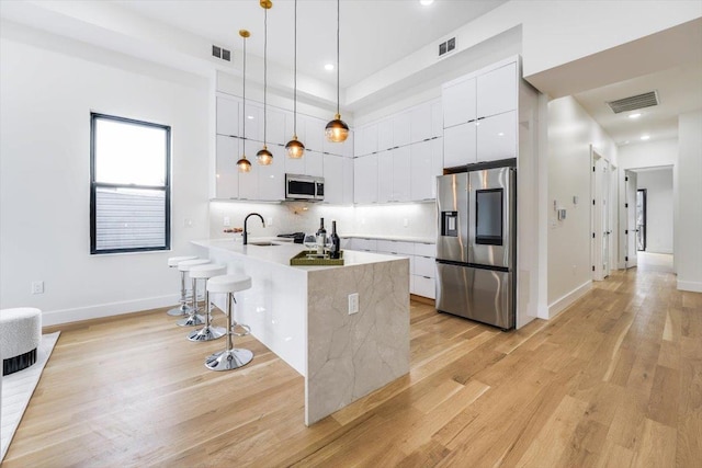 kitchen with white cabinetry, a kitchen breakfast bar, visible vents, and appliances with stainless steel finishes