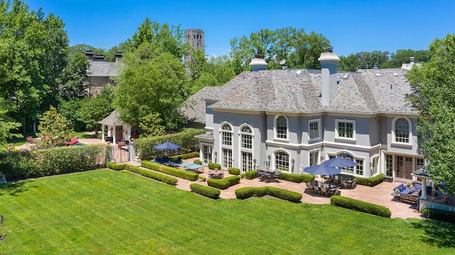 rear view of property featuring a lawn and a patio