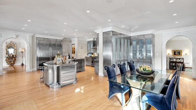 dining area with ornamental molding, light hardwood / wood-style floors, and ornate columns