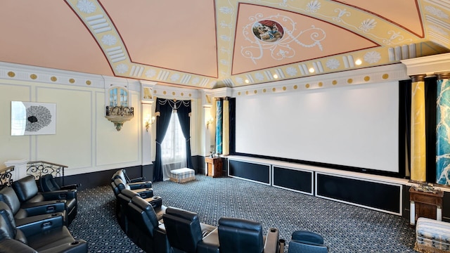 carpeted home theater featuring a towering ceiling and crown molding