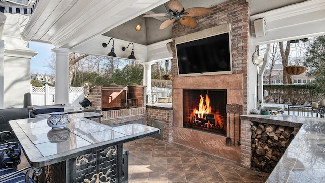 view of patio featuring an outdoor bar, an outdoor brick fireplace, and ceiling fan