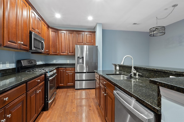 kitchen with light hardwood / wood-style flooring, a chandelier, stainless steel appliances, dark stone countertops, and sink