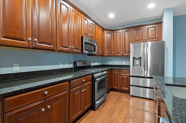 kitchen with dark stone countertops, light wood-type flooring, and appliances with stainless steel finishes