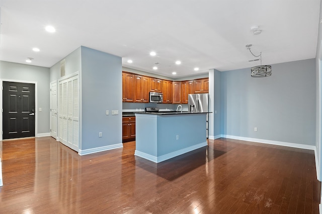 kitchen featuring stainless steel appliances, sink, an inviting chandelier, an island with sink, and dark hardwood / wood-style floors