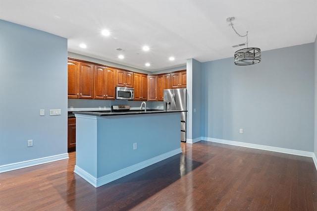 kitchen featuring sink, an island with sink, dark hardwood / wood-style floors, a notable chandelier, and appliances with stainless steel finishes